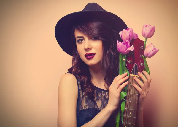 Portrét mladé krásné ženy s kytarou a tulipány — Stock fotografie