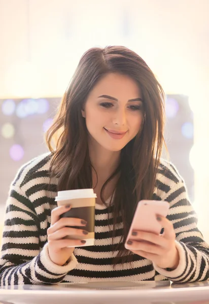 Vrouw met kopje koffie en mobiele telefoon — Stockfoto