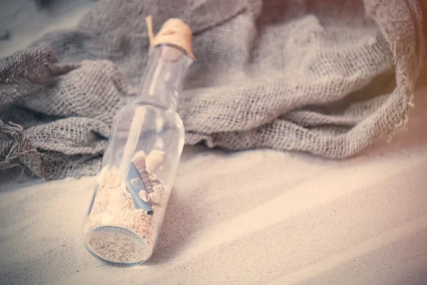 Botella de recuerdo y red de pesca en la arena — Foto de Stock