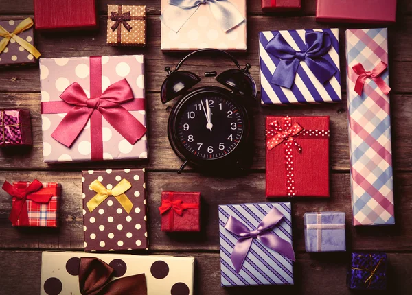 Színes ajándékokat és az óra az asztalon — Stock Fotó