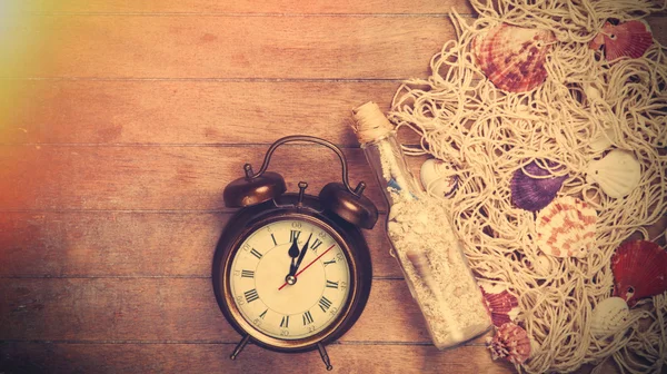 Reloj despertador retro y red con conchas y botella — Foto de Stock