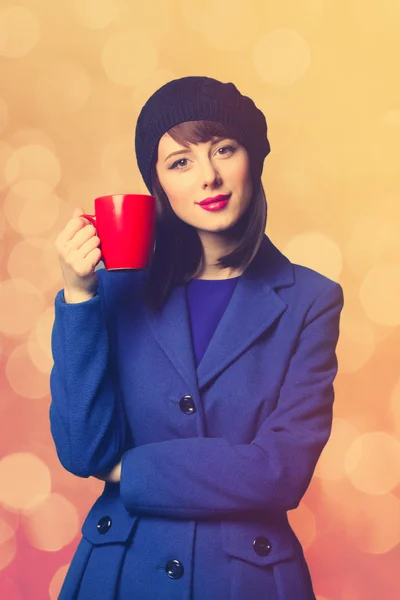 Frau im blauen Kleid mit roter Tasse — Stockfoto