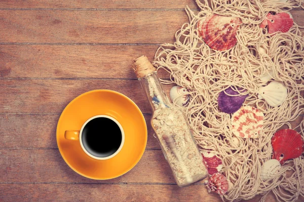 Cup and net with shells and bottle — Stock Photo, Image