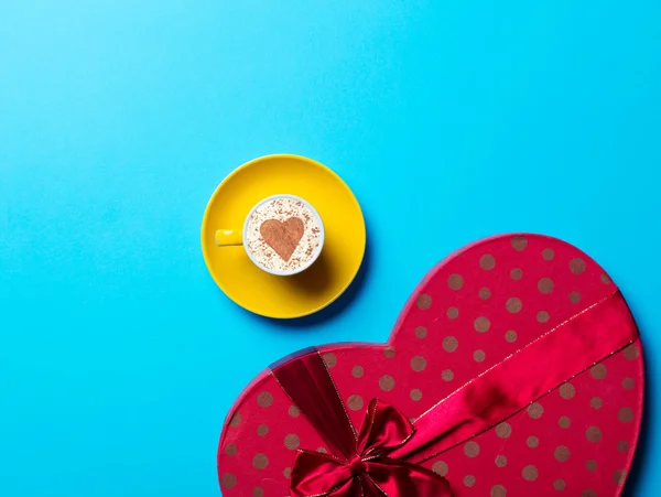 Yellow cup of coffee and gift — Stock Photo, Image
