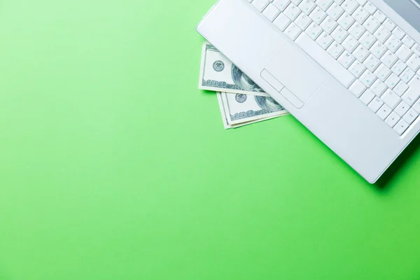 Деньги и ноутбук на зеленом — стоковое фото