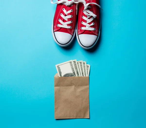 Geld en rode gumshoes op de blauwe — Stockfoto