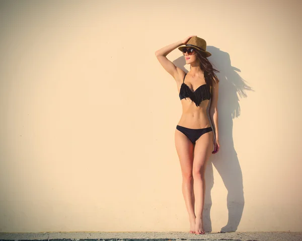 Beautiful young woman standing near the white wall — Stock Photo, Image