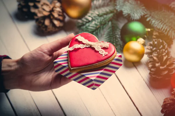 Vrouwelijke hand met een cookie en cadeau — Stockfoto