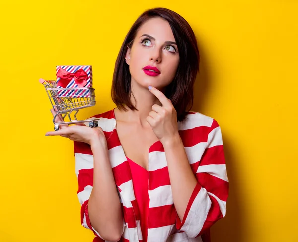 Young woman with gift and cart — Stock Photo, Image