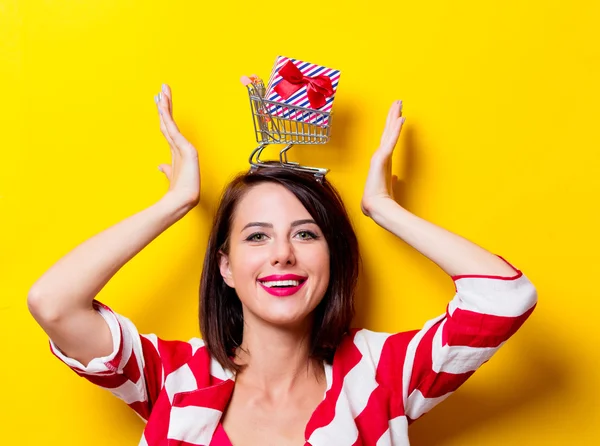 Giovane donna con regalo e carrello — Foto Stock