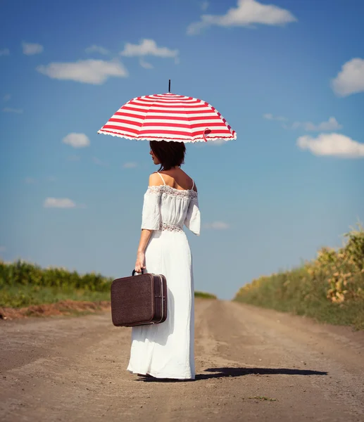 Mladá žena s kufrem a deštníkem — Stock fotografie