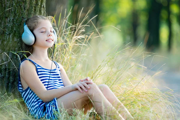 Menina com fones de ouvido na floresta — Fotografia de Stock