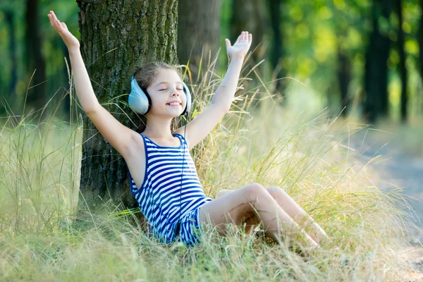 Ragazza con gli auricolari nella foresta — Foto Stock