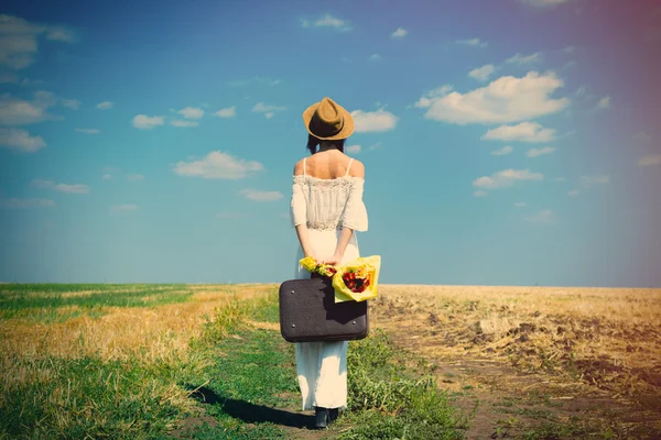 Junge Frau mit Koffer und Blumenstrauß — Stockfoto