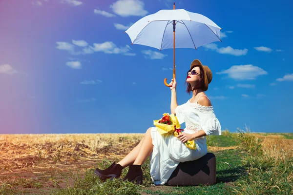 Ung kvinna med resväska, paraply och bukett — Stockfoto