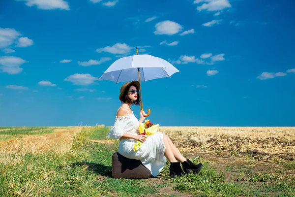 Young woman with suitcase, umbrella and bouquet — Stock Photo, Image