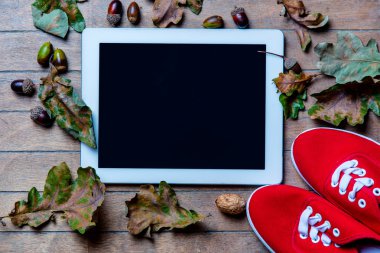 Tablet, lastikbotlar ve düşen yapraklar