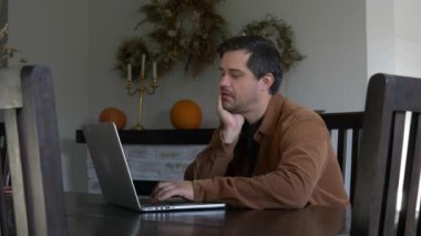 Adam evde dizüstü bilgisayarla çalışıyor.