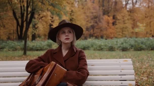 Style Girl Brown Coat Suitcase Sitting Bench Autumn Park — Stock Video