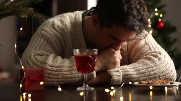 Muž v depresivní sedí sám u stolu a pije vánoční svařené víno 