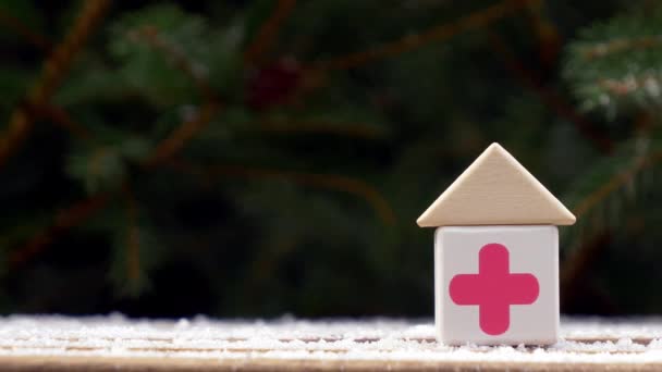 Kleines Spielzeughaus Mit Rotem Kreuz Auf Einem Schneeteller Neben Dem — Stockvideo