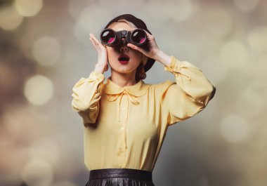 Gri arka planda dürbünü olan klasik elbiseli güzel bir kız.