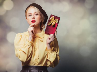 Gri arka planda hediyeli, klasik elbiseli güzel bir kız.