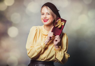 Gri arka planda hediyeli, klasik elbiseli güzel bir kız.