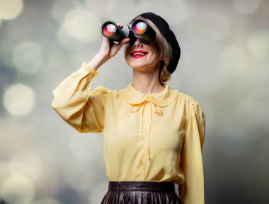 Gri arka planda dürbünü olan klasik elbiseli güzel bir kız.