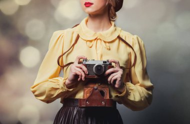 Gri arka planda fotoğraf makinesi olan klasik elbiseli güzel bir kız.