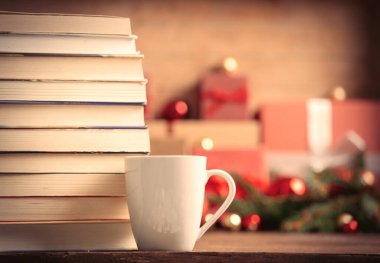 Arkaplanda Noel hediyeleri olan bir yığın kitap ve kahve.