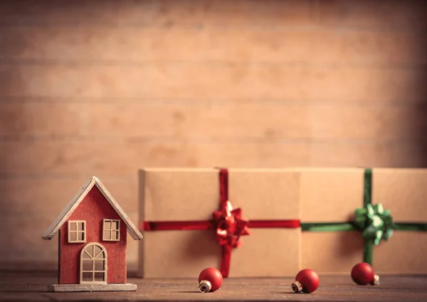 木制桌子上的小玩具屋和圣诞礼物 — 图库照片