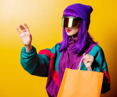 VR gözlüklü ve 80 'lerin eşofmanlı, sarı arkaplanlı stil kadın.