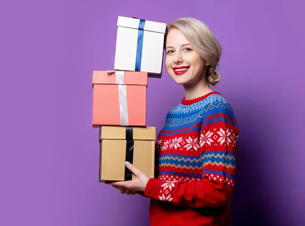 穿着圣诞毛衣 背景为紫色礼品盒的漂亮女人 — 图库照片