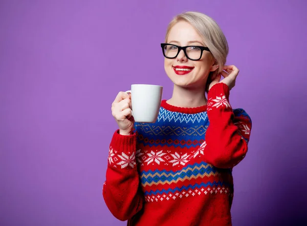 美しい女性でクリスマスセーターにコーヒーカップの紫の背景 — ストック写真