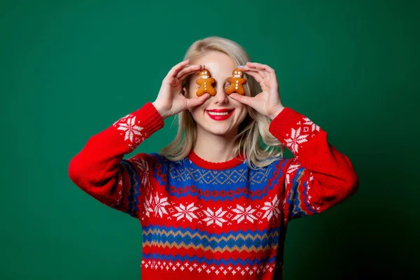 穿着圣诞毛衣的漂亮女人 绿色背景的姜饼男饼干 — 图库照片