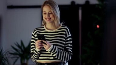 Noel süslemesinde cep telefonu olan güzel bir kadın