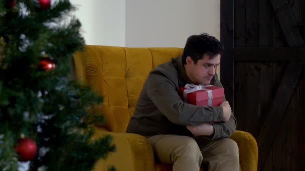Szomorú Fickó Egy Ajándékkal Aki Karosszékben Karácsonykor — Stock videók