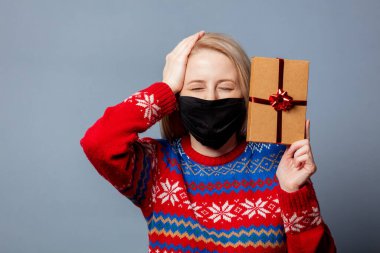 Gri arkaplanlı, Noel süveteri içinde güzel bir sarışın.