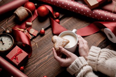 Kadın eli, bir fincan kahve ve kurabiyeyi paketleme zamanında ahşap masada tutar.