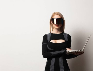 VR gözlüklü sarışın android kadın ve beyaz arka planda dizüstü bilgisayar..