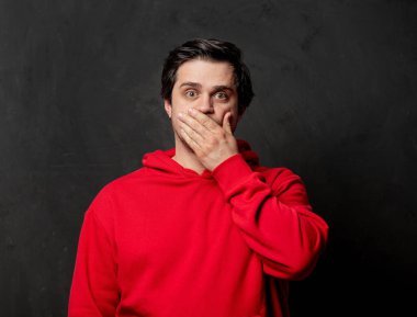 Siyah arka planda kırmızı kazaklı, beyaz, şaşırmış bir adam.