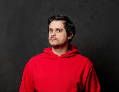 Siyah arka planda kırmızı kazaklı, beyaz, şaşırmış bir adam.