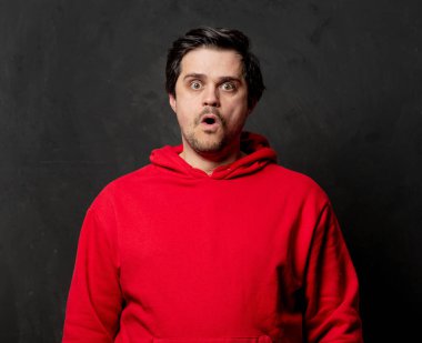 Siyah arka planda kırmızı kazaklı beyaz üzgün adam.