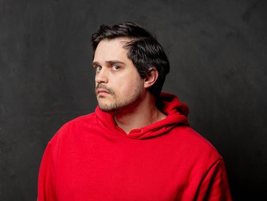 Siyah arka planda kırmızı kazaklı, beyaz, şaşırmış bir adam.