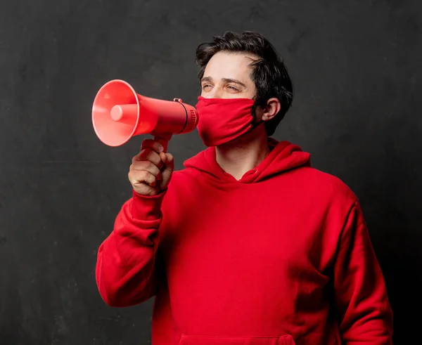 穿着红色运动衫和面罩的家伙拿着暗色背景的扩音器 — 图库照片