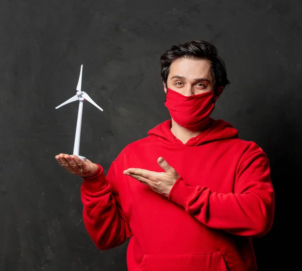 Kırmızı Kazaklı Maskeli Adam Arka Planda Küçük Bir Rüzgar Jeneratörü — Stok fotoğraf