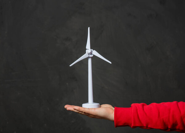 male hand hold little wind generatior on dark background 