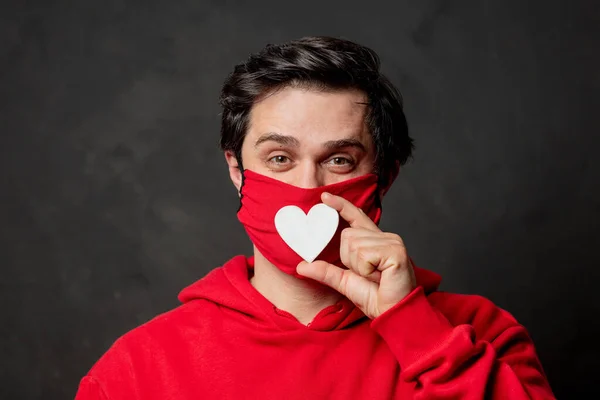 Kırmızı Kazaklı Maskeli Adam Koyu Arkaplanda Kalp Şeklinde Duruyor — Stok fotoğraf