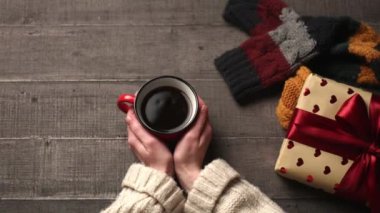 Kadın eli kahve ve hediye kutusuyla ahşap masada. 